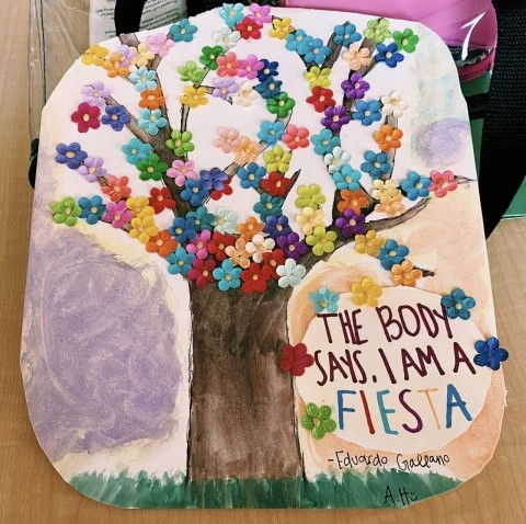 A painting of a tree with fabric flowers glued all over the top